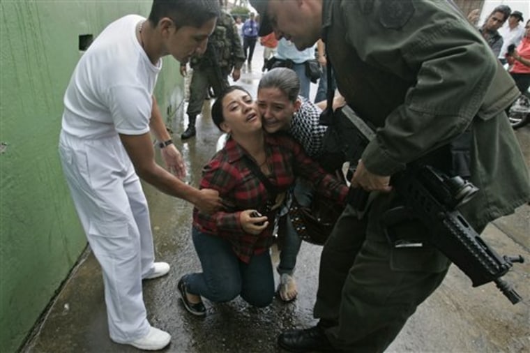 A police officer and a paramedic comfort the crying relatives of a slain police officer in front of the police station in Caloto, southwest Colombia, on Tuesday. 